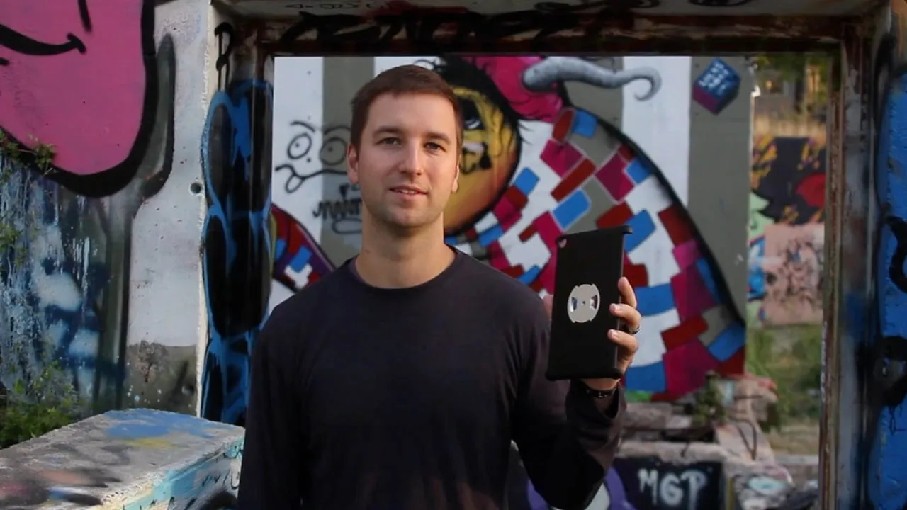 Chris holding a Deohako iPad case in front of a graffiti wall