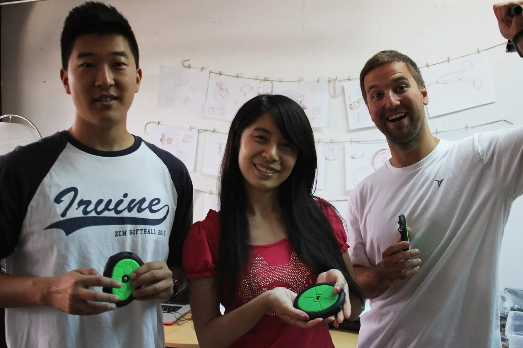 Three members of the Tooga team smiling and holding green camera mounts