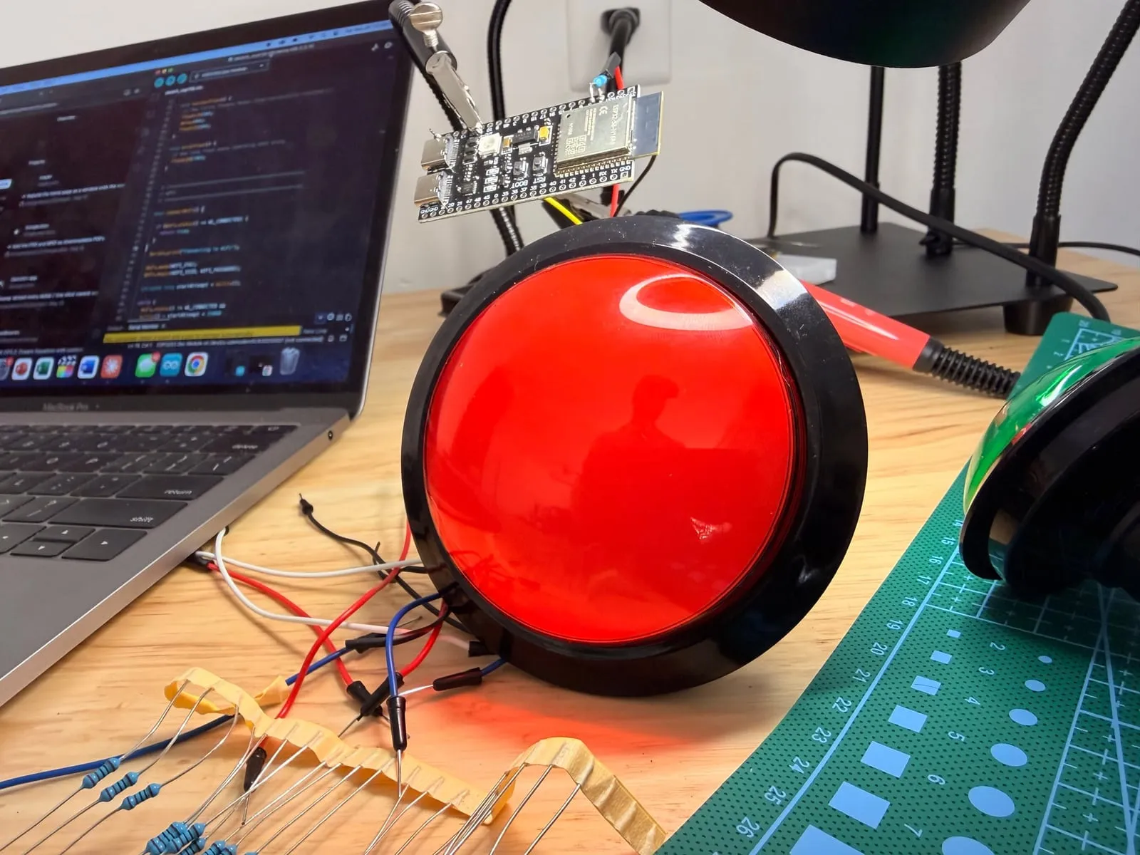 A large red arcade button wired to an ESP32 board on a workbench